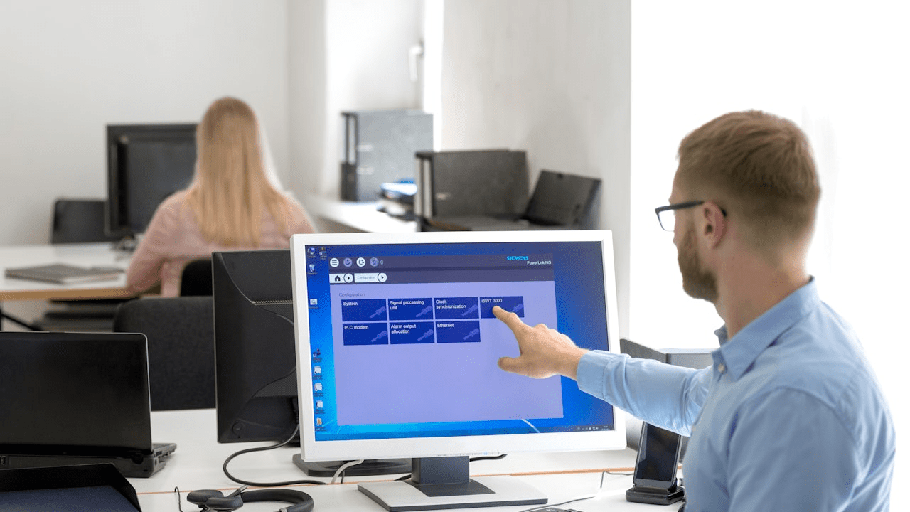 Person in black shirt standing against white wall, holding white object with blurred background